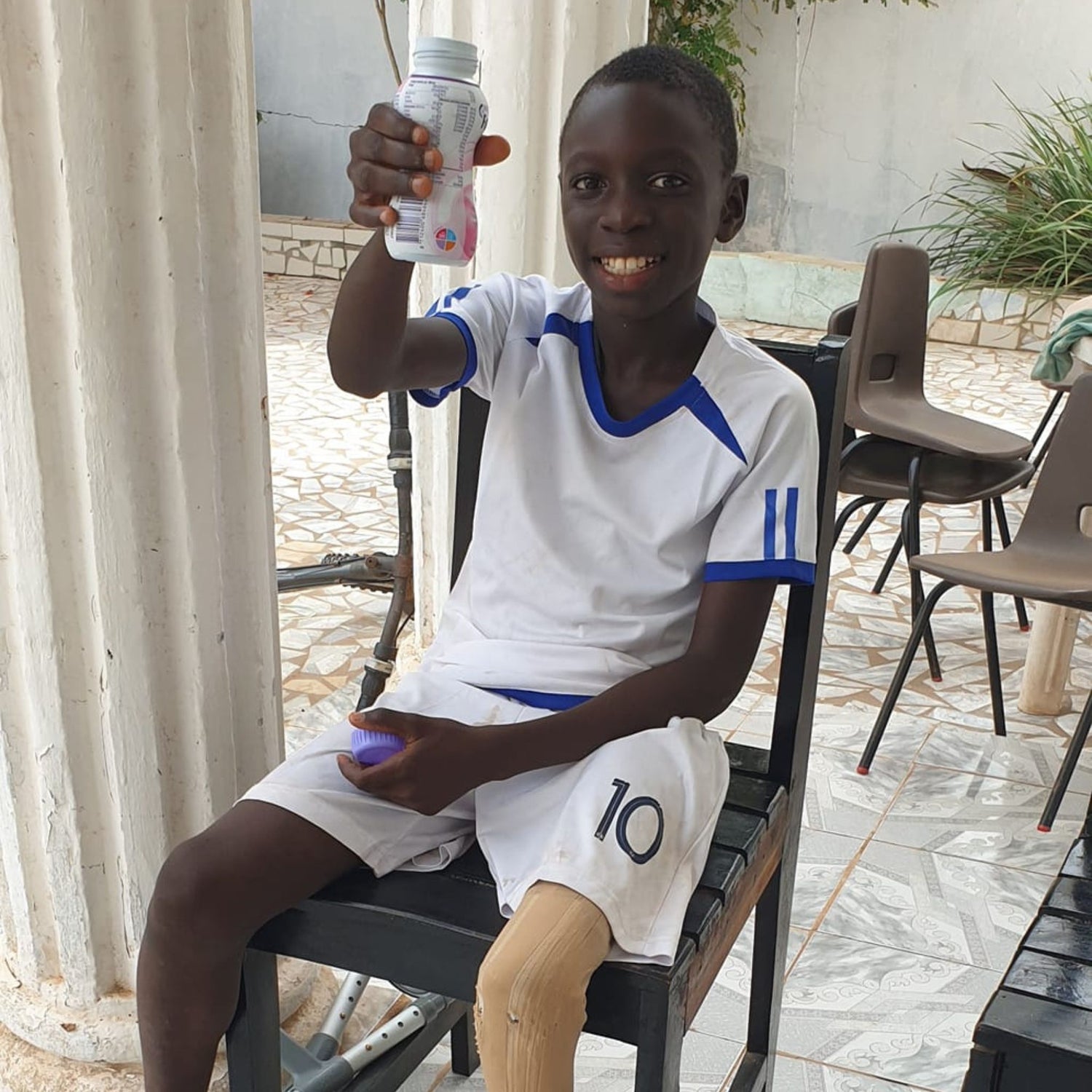 The Glove Project child amputee sitting with a milkshake smiling at camera